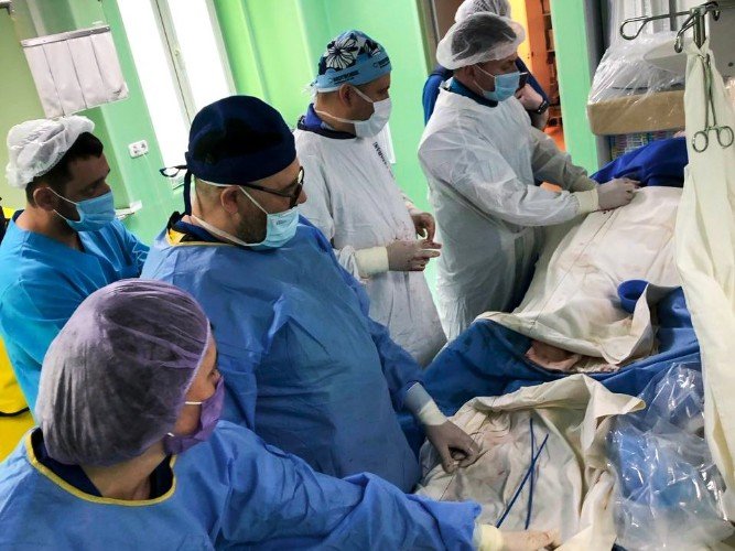 врачи стоят около операционного стола