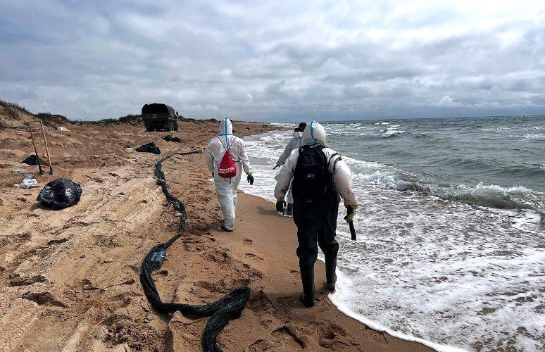 люди в химзащите идет по берегу моря