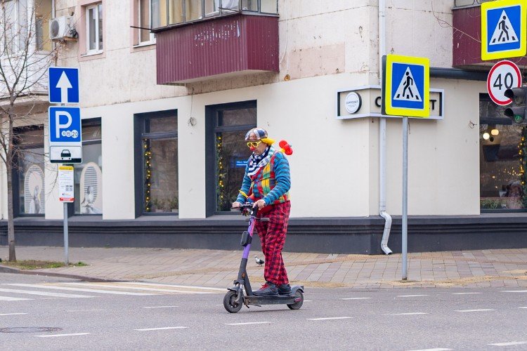 клоун едет на самокате