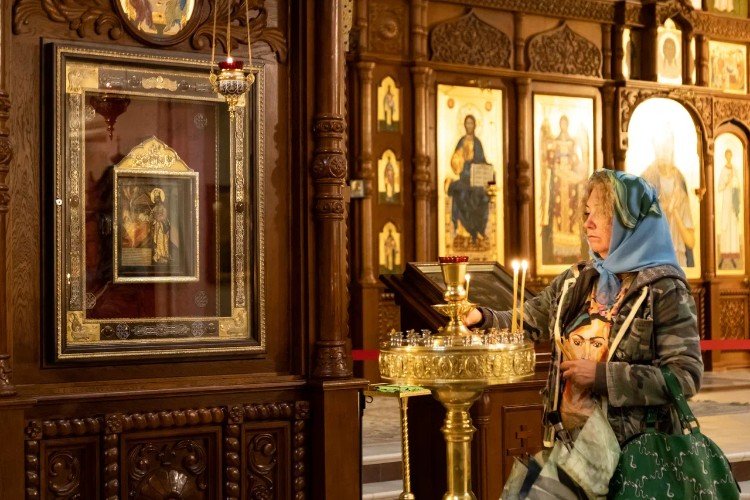 женщина ставит свечу в церкви