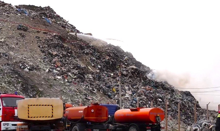 машины стоят у горы мусора