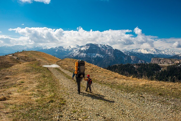 турсит идет с ребенком по тропе в горах