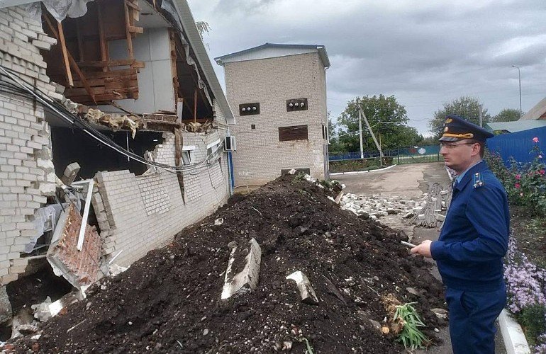 мужчина в форме стоит у рухнувшей стены