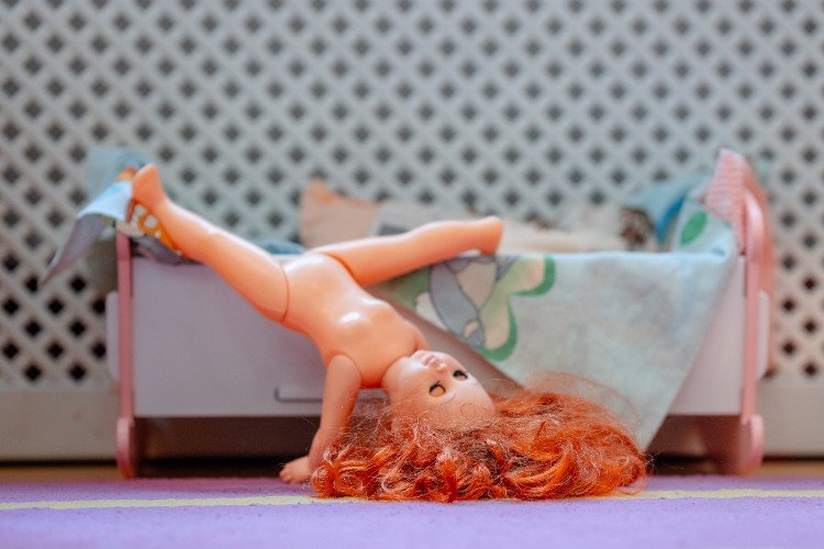 голая кукла лежит у кроватки