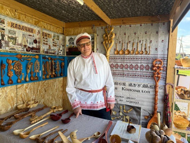 мастер по резьбе ложек стоит и экспонатов