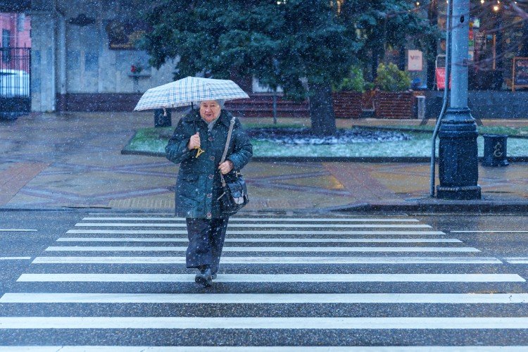 женщина под зонтом переходит дорогу