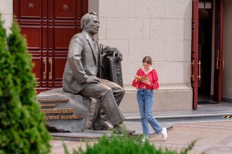 Девушка читает книгу рядом с памятником