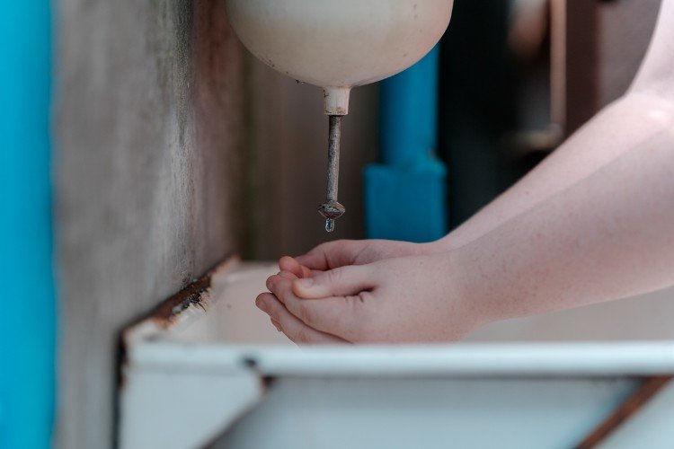 Человек пытается набрать воды в рукомойнике