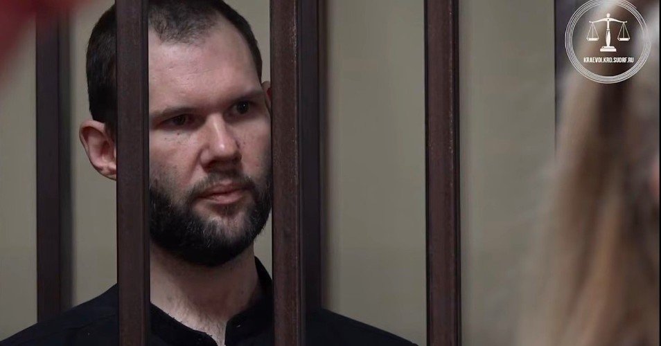 мужчина стоит за решеткой