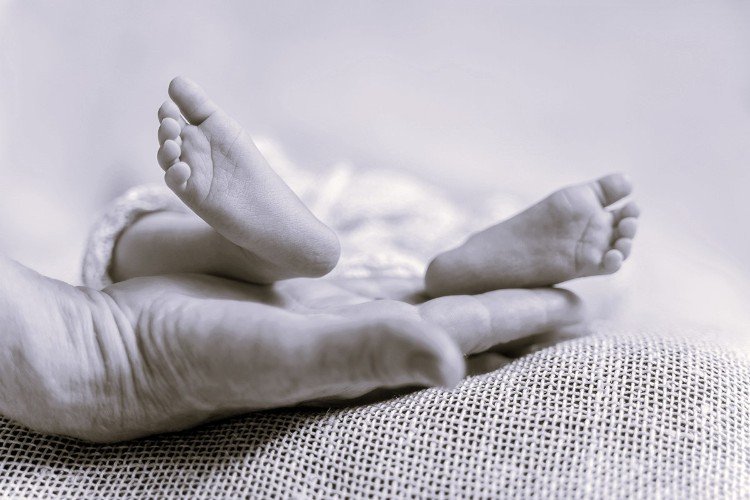 рука держит ножки младенца