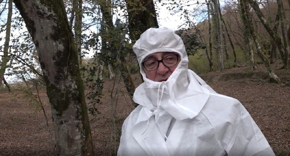 Ветеринар стоит в комбезе в лесу