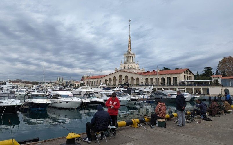 рыбаки сидят на пирсе морпорта Сочи