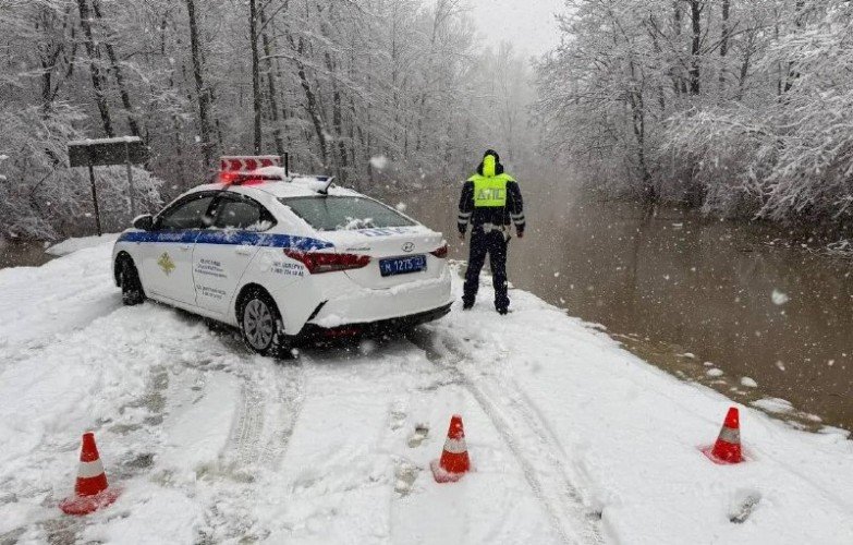 экипаж ДПС стоит у затопленной дороги