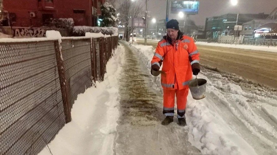 Работник мэрии посыпает песком улицы города