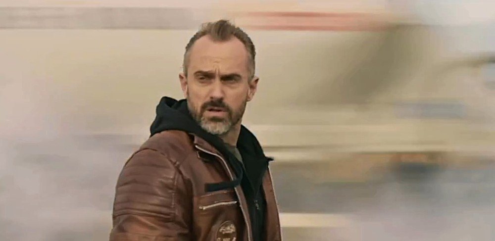 актер стоит на фоне дороги