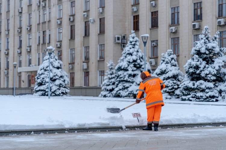 рабочий убирает снег