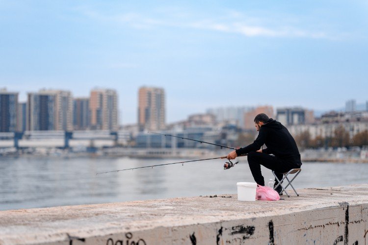 Мужчина ловит рыбу на фоне многоэтажных домов