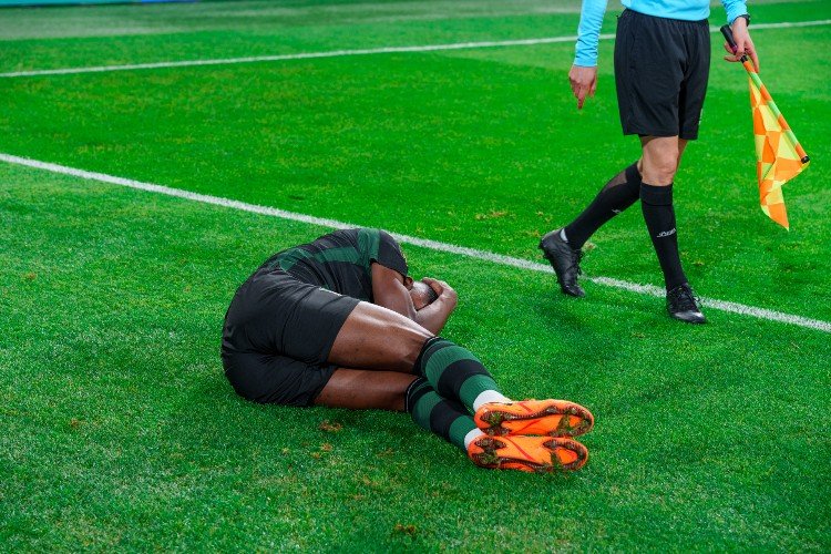 футболист лежит на поле