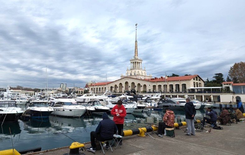 люди сидят на пирсе морпорта Сочи