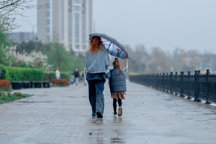 женщина с девочкой идут под зонтом