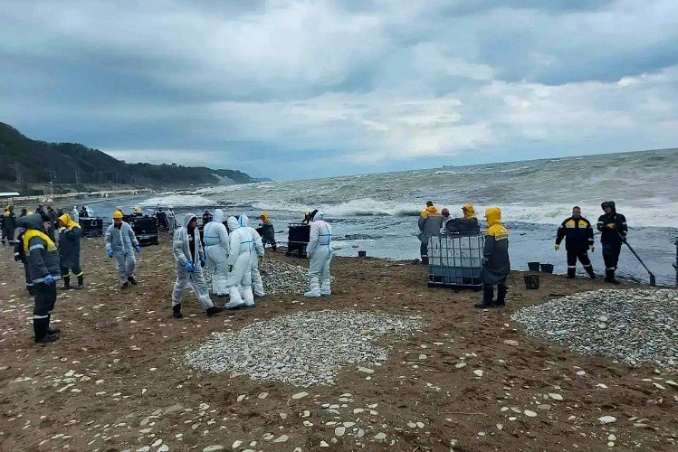 Люди в защитных костюмах работают на берегу моря