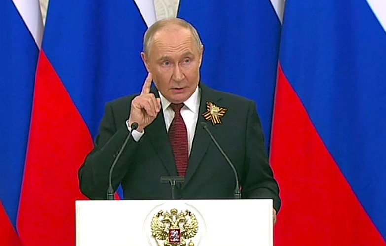 Путин стоит за трибуной