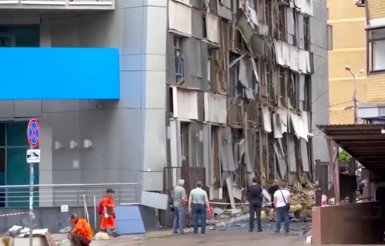люди стоят около разрушенного дома