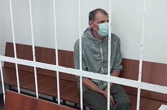 мужик сидит за решеткой