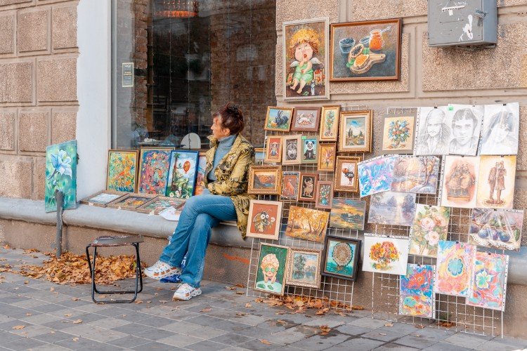 Женщина продаёт картины на улице Чапаева в Краснодаре