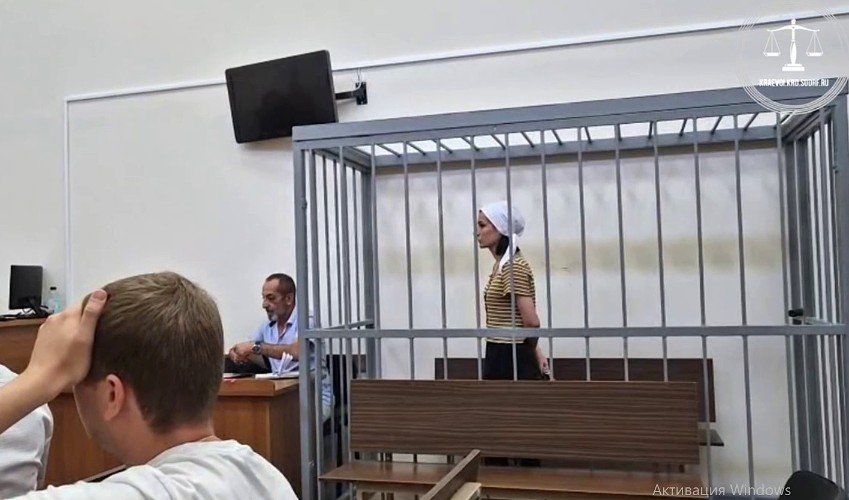 женщина стоит за решеткой в зале суда