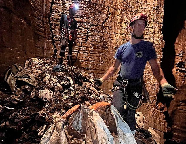 мужчины стоят на горе мусора в пещере