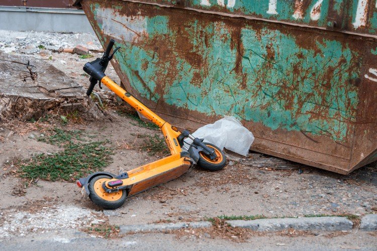 самокат лежит у контейнера