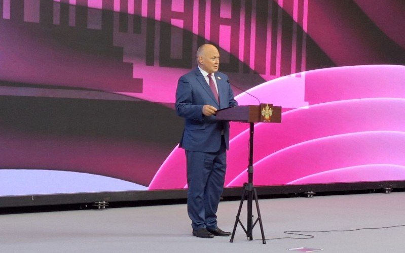 Мужчина стоит за трибуной на сцене