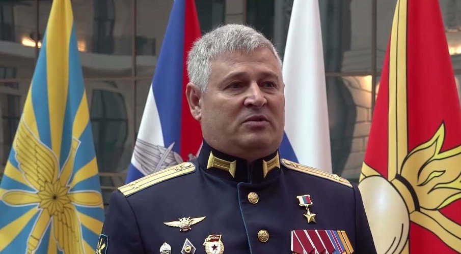 военный в форме стоит у знамен