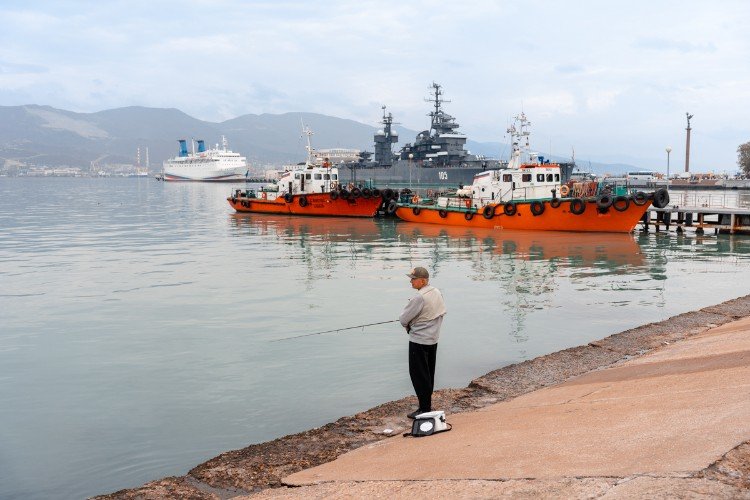 рыбак стоит с удочкой у моря