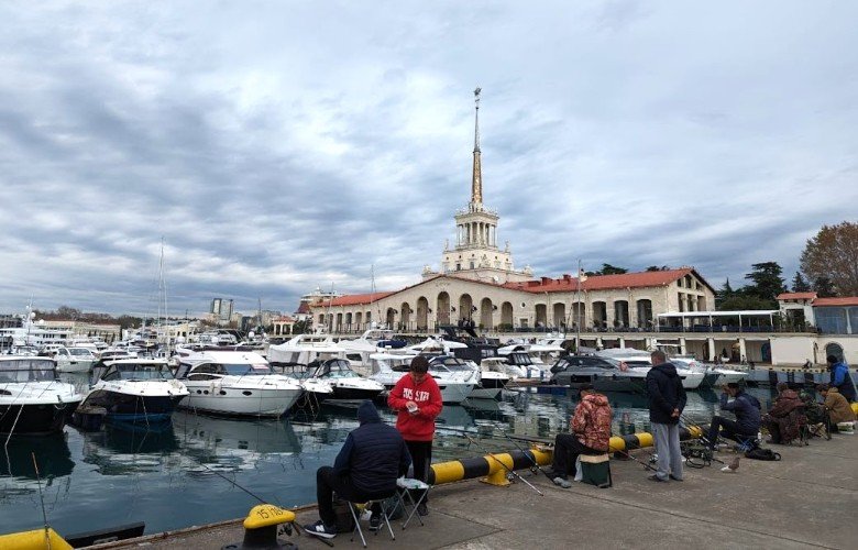 люди сидят на пирсе морпорта Сочи