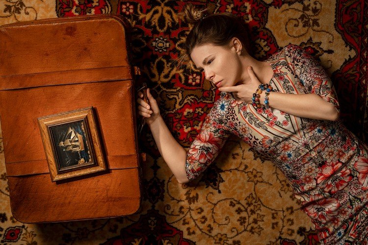 Красивая женщина лежит рядом с чемоданом