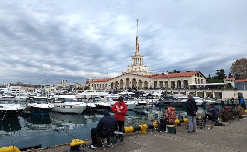 Рыбаки сидят на пирсе морвокзала Сочи