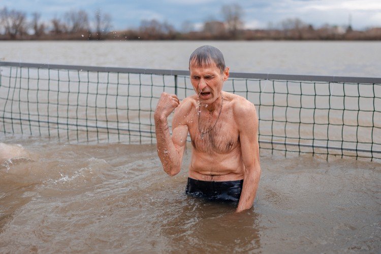 Мужчина крестится в воде