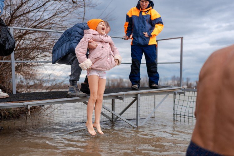 Девочка кричит, пока её окунают в воду