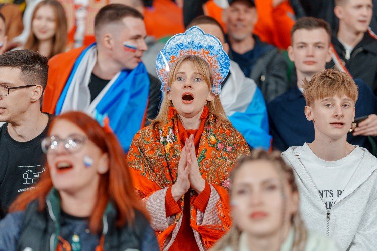 Девушка в кокошнике молится на стадионе