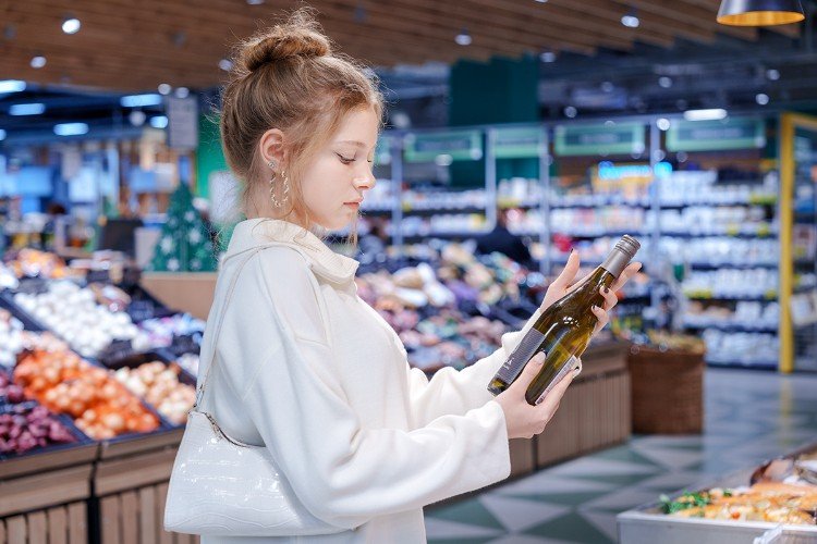 Девушка оценивает бутылку вина