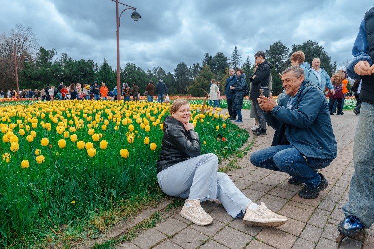 люди фотографируются около клумбы
