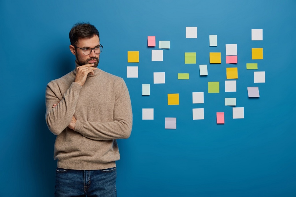 bearded-male-organizing-his-tasks-using-sticky-notes.jpg
