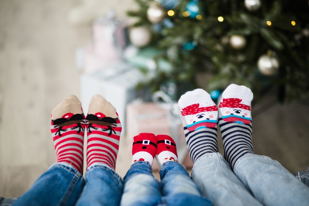 Семья из трех человек сидит у рождественской елки в нарядных носках