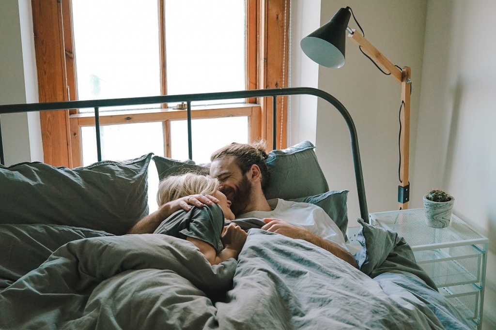 Мужчина и женщина лежат, обнявшись, в постели
