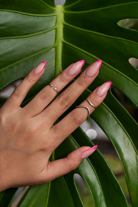 Женские руки с гель-лаком на ногтях на фоне листьев монстеры