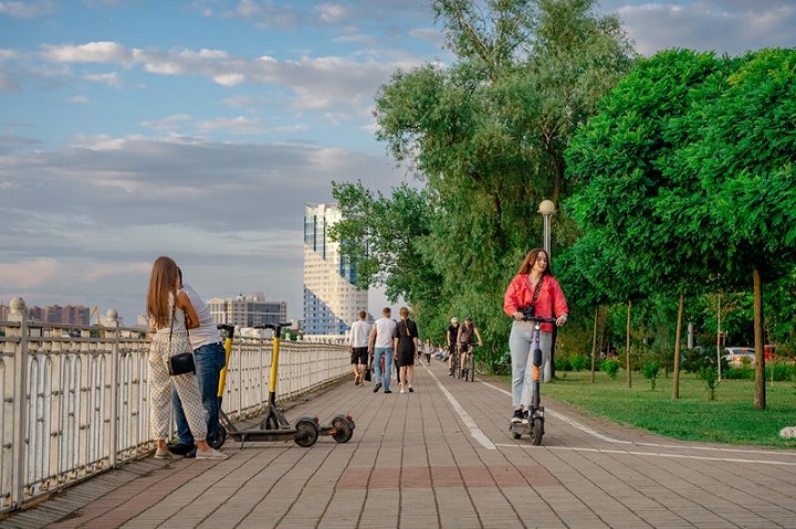 Девушка едет на электросамокате вдоль набережной Кубани в Краснодаре 