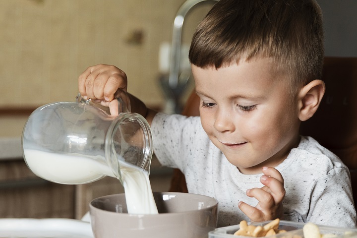 Маленький мальчик наливает себе в стакан молоко