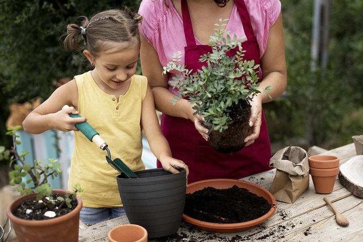 Девочка с мамой пересаживают растение в горшок